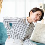 ソファに座って腰を押さえる女性