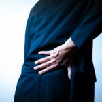 スーツ姿で腰を押さえる男性