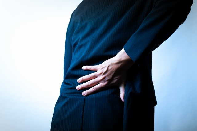 スーツ姿で腰を押さえる男性